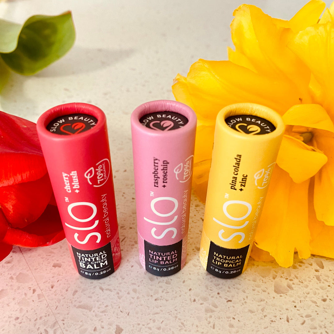 Eco Fox lip balm trio displayed with natural props, showcasing Cherry & Blush, Raspberry & Rosehip, and Pina Colada + zinc for a lifestyle setting.