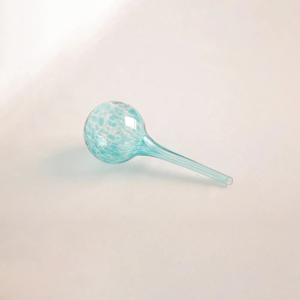 Decorative aqua-toned glass plant feeder with swirls of turquoise and green, ideal for houseplants and patio pots.