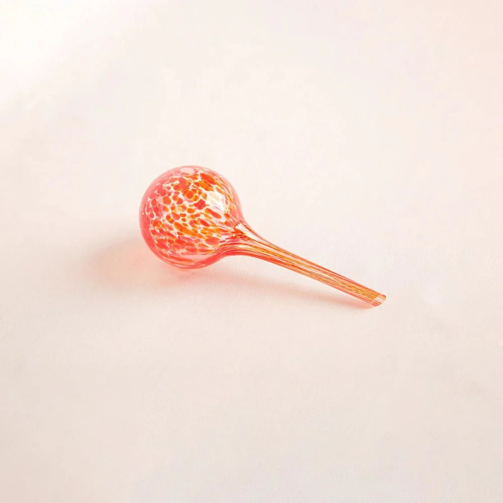 Hand-blown glass plant watering globe in fiery red, orange, and yellow tones, perfect for indoor and outdoor plants.